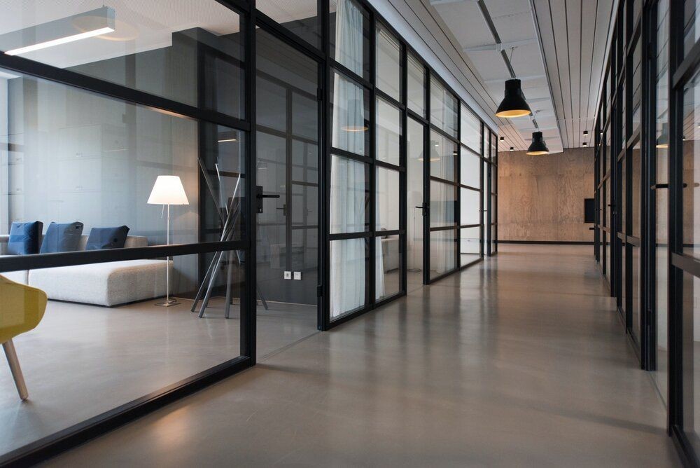 Modern office corridor with glass partitions and ambient lighting.